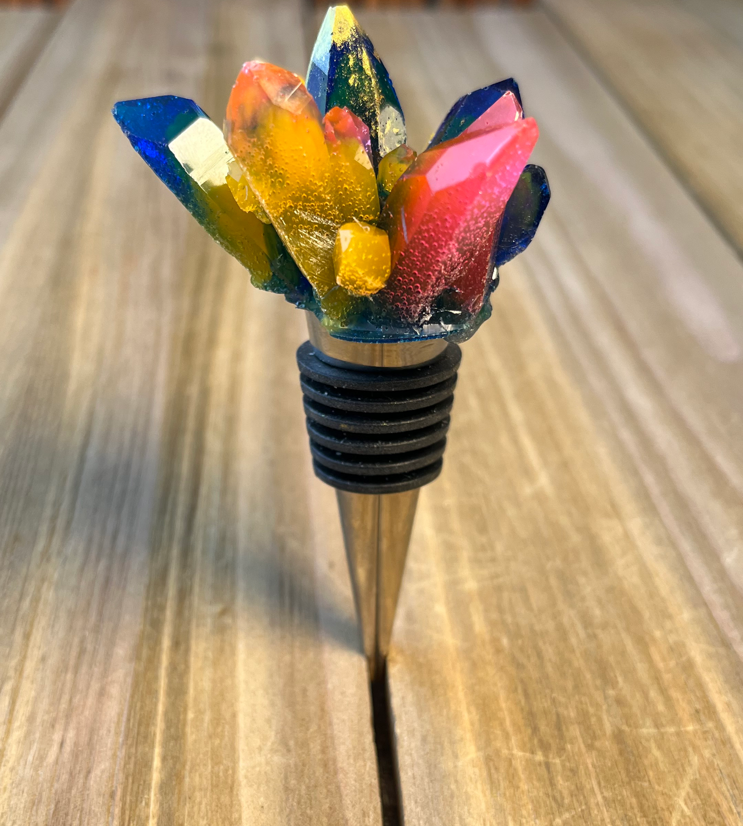 silver wine stopper with multicolored handmade epoxy crystal on top with eight different sized points with orange, pink, dark blue and gold colors