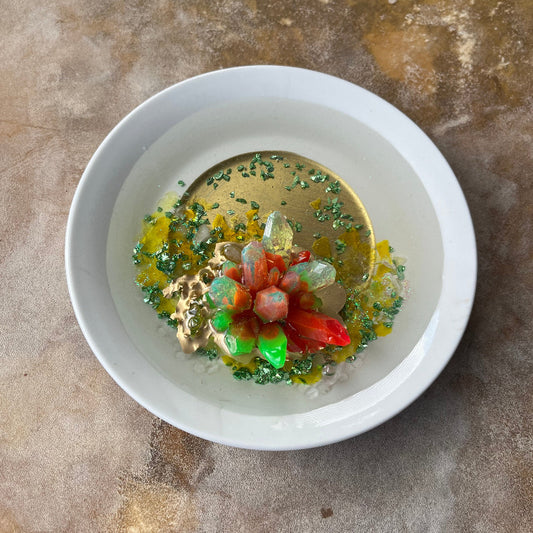 Orange and Green Resin Crystal on Dark green crushed glass overhead view