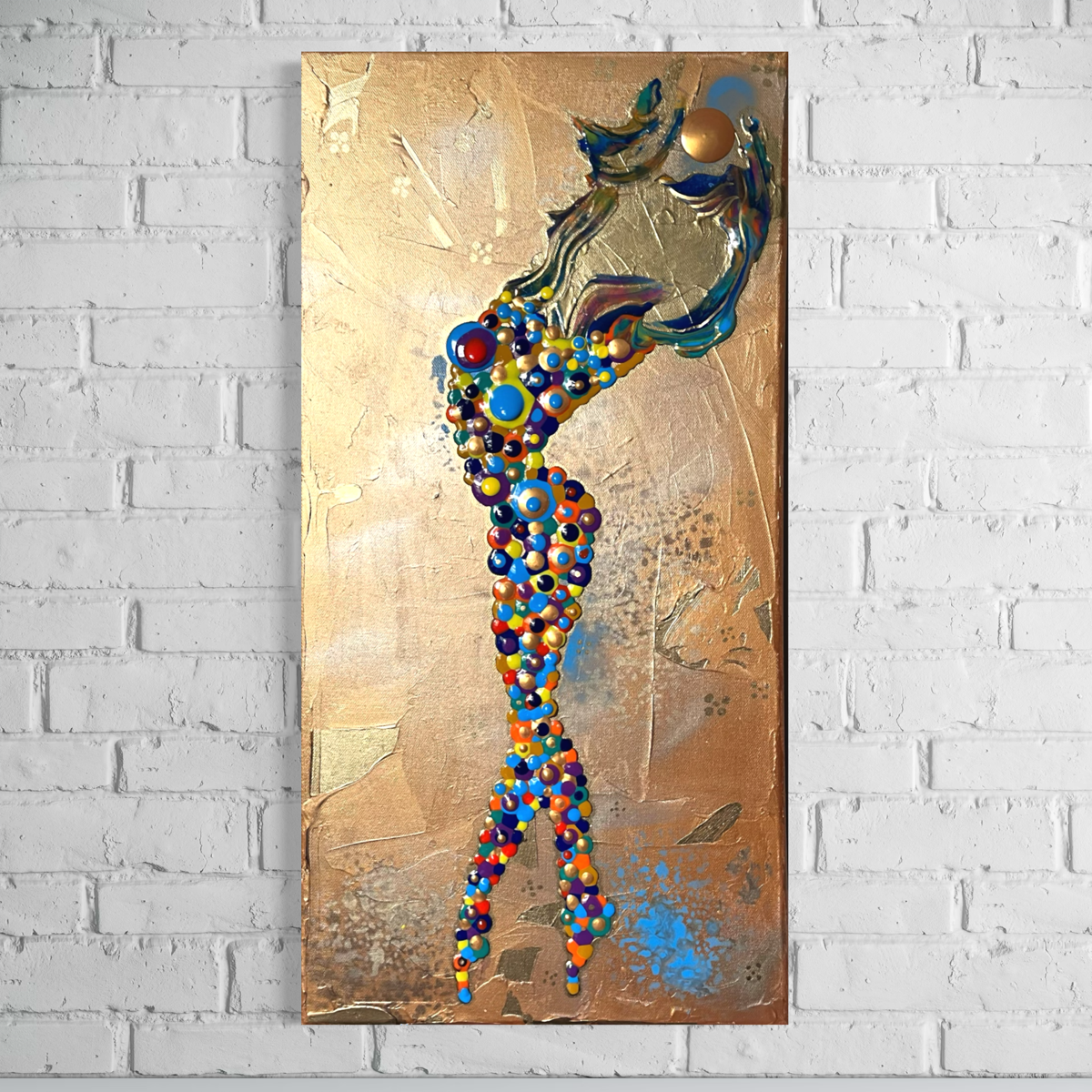 gold abstract of a girl made of circles holding up the sun over a gold background hanging on a white brick wall
