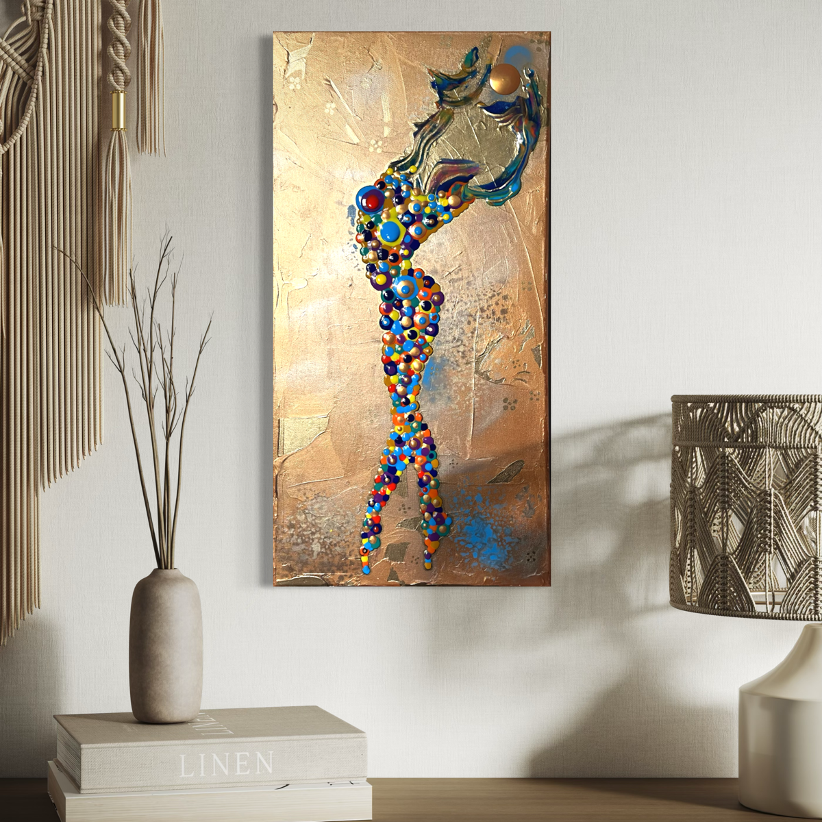 gold abstract of a girl made of circles holding up the sun over a gold background hanging on a blue wall

