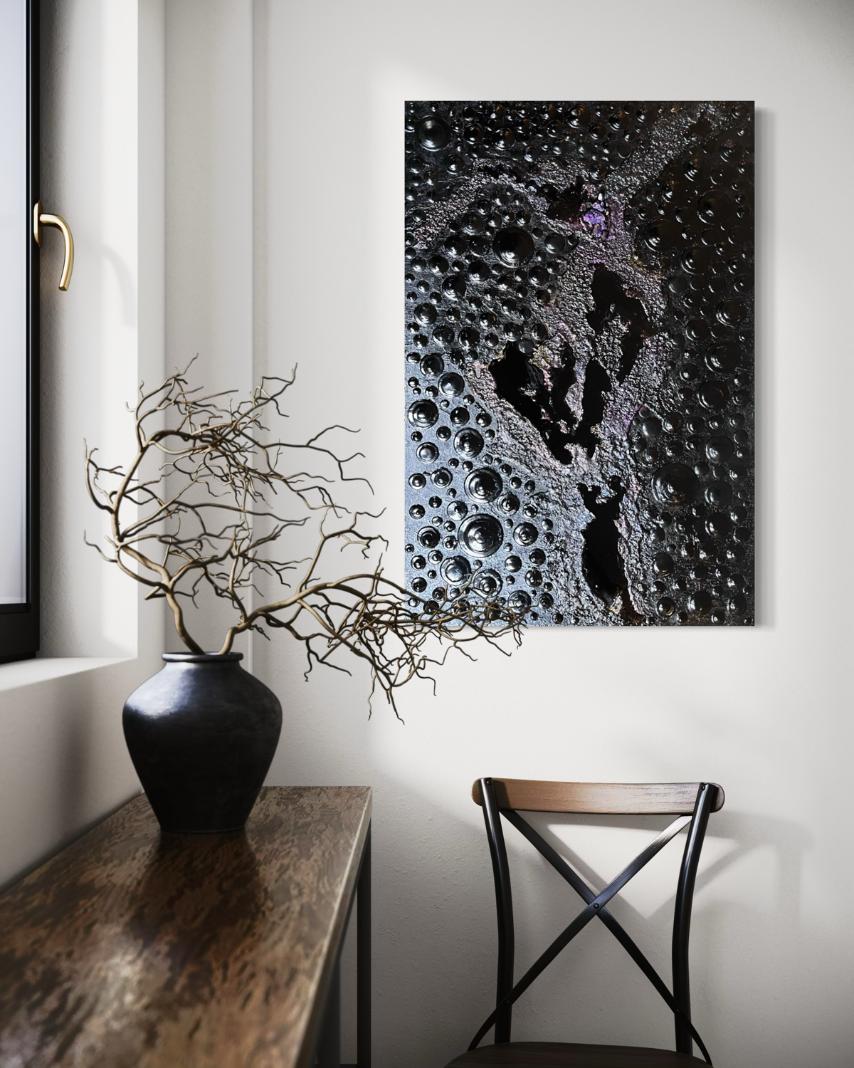 A rectangular abstract painting on canvas hanging on a white painted brick wall. The artwork features a dark black textured around epoxy smooth lakes.  hung in a room with white walls a chair and a vase
