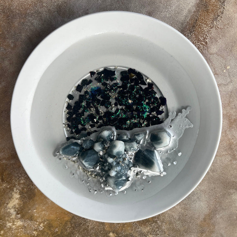 Grey Resin Crystal Cluster sitting on Black Crushed Glass overhead view