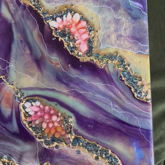 video of a purple and orange crystal geode epoxy piece sitting on a green couch